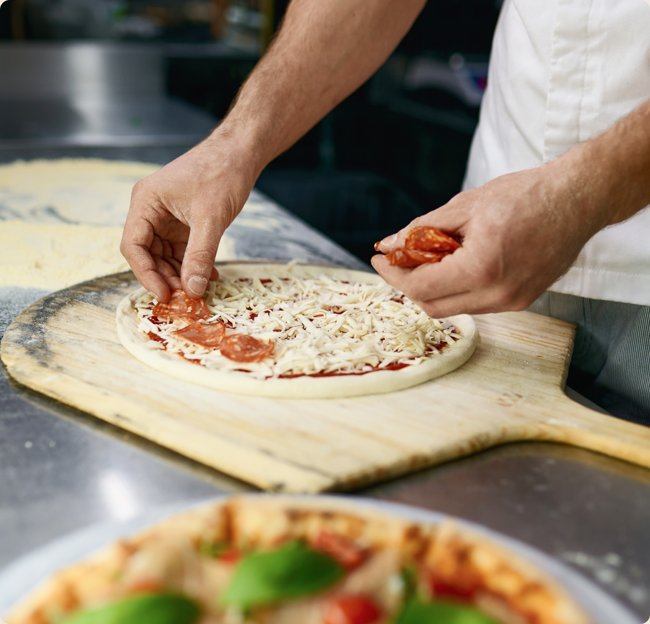 Pizzaiolo przygotowujący świeżą pizzę w kuchni Burgery Kupiec